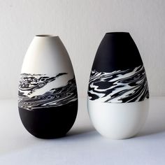 two black and white vases sitting next to each other