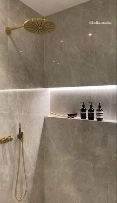 the shower head is mounted on the wall next to the shelf in the bathroom,