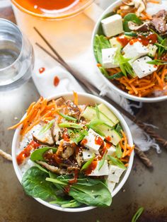 two bowls filled with salad and dressing on top of a table