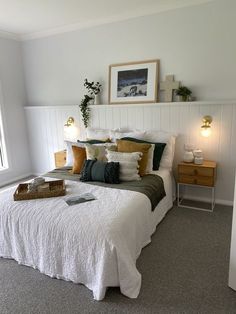 a bed with white sheets and pillows in a bedroom next to a window, framed pictures on the wall