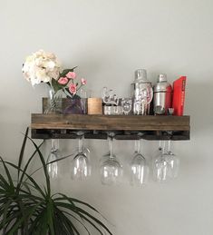 a shelf with wine glasses and flowers on it