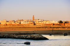 a small boat is in the water near a beach with buildings and people on it