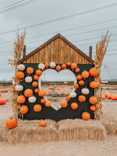 an outdoor display with pumpkins and hay in the shape of a house, surrounded by corn stalks