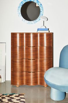 a blue chair sitting next to a wooden dresser