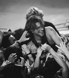 black and white photograph of woman in crowd with arms around her head