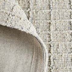 an up close view of a rug with white and gray colors on it, including the corner of a piece of fabric that has been cut in half