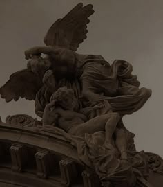 a statue on top of a building with angel wings and cherubs around it