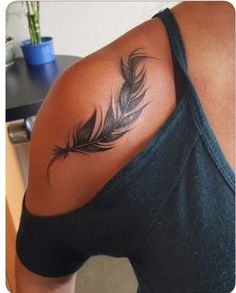 a woman's back with a tattoo on her shoulder and a feather in the middle