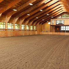 an empty horse barn with wooden walls and windows on each side, in the middle of a dirt floor