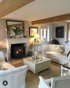 a living room filled with white furniture and a fire place in the middle of it