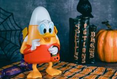 an orange and white ducky figure on a table with halloween decorations in the background