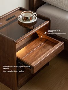 an open drawer with a cup and saucer on it, next to a bed