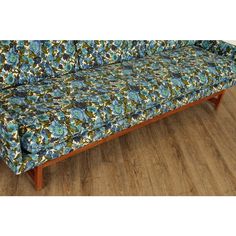 a blue floral couch sitting on top of a hard wood floor