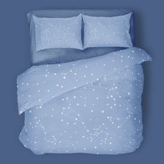 a blue comforter with white stars on it and two pillows in the background,