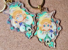 two keychains with anime characters on them sitting on the floor next to each other