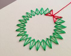 an ornament made out of green thread on a white surface with a red string