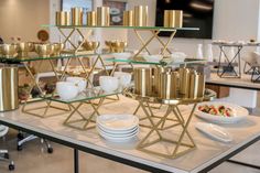 a table topped with plates and bowls filled with gold colored cups, saucers and spoons