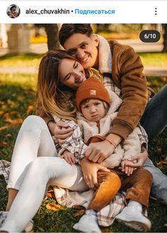 a man and woman are sitting on the grass with their child