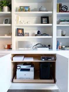 an open cabinet with printer and other items on the shelves in front of it,