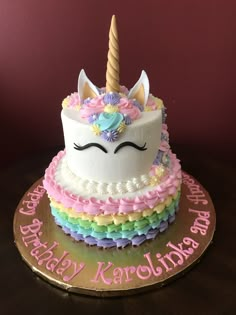 a birthday cake with a unicorn face and rainbow ruffles on the bottom layer