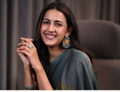 a woman sitting in a chair with her hand on her hip and smiling at the camera