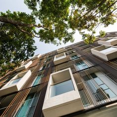 looking up at the side of a tall building with lots of windows and balconies