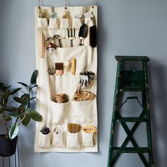 a wall hanging on the side of a blue wall next to a green ladder and potted plant