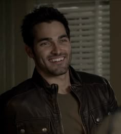 a smiling man in a leather jacket looking at the camera