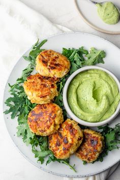 crab cakes with guacamole sauce on a plate next to a small bowl