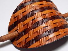 an orange and brown basket sitting on top of a white table next to two wooden spoons