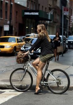 a woman is riding her bike down the street