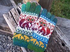 two knitted mittens sitting on top of a wooden bench