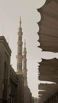 a tall building with a clock on it's side next to other buildings and umbrellas