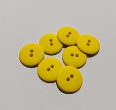 six yellow plastic buttons sitting on top of a white surface