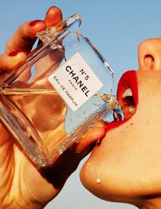 a woman with her mouth open holding a bottle of chanel perfume