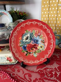 a red plate sitting on top of a table next to other plates and vases