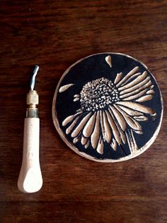 a wooden table topped with a black and white flower next to a small toothbrush