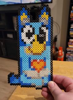 a hand holding up a small beaded phone case with a cartoon character on it