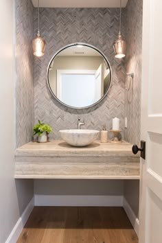 a bathroom sink sitting under a mirror next to a light on top of a wooden floor