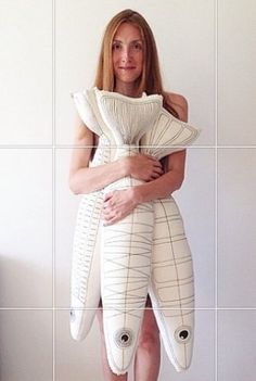 a woman standing in front of a white wall holding a large piece of art that looks like a fish