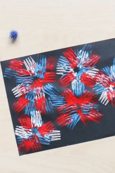 a piece of paper with red, white and blue flowers on it sitting on a table