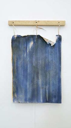 a piece of blue paper hanging on a wooden hanger next to a white wall