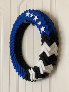 a wreath made out of paper stars hanging on a door handle with white and blue ribbon