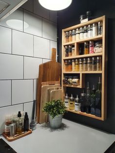 a kitchen counter with spices on it and cutting boards in front of the shelves that hold bottles