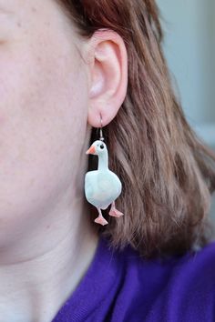 a close up of a person wearing earrings with a bird on it's ear