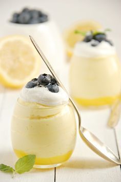 lemon custard with blueberries and whipped cream in small glass jars on a white table