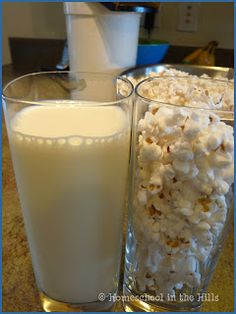 two glasses filled with milk and popcorn on a table