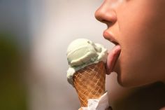 a close up of a person eating an ice cream cone with their tongue hanging out