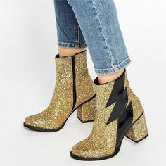 Make a bold statement with our Gold Glitter Thunderbolt Round Toe Block Heel Ankle Boots. These dazzling boots feature a striking thunderbolt design, paired with a round toe and block heel, creating a glamorous and trendy footwear choice for any fashion-forward occasion. Handcrafted US sizing. Fits true to size. Heel height: 3" / 80 mm approx Product measurements were taken using size 8. Please note that measurements may vary by size. Eye-catching gold glitter material for a stunning and festive Gold Glitter Heels, Gold Boots, Glitter Boots, Chunky Heel Ankle Boots, House Of Holland, Glitter Heels, Block Heel Ankle Boots, New Rock, Glitter Shoes