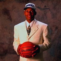 a man in a suit and tie holding a basketball with the words spalding on it